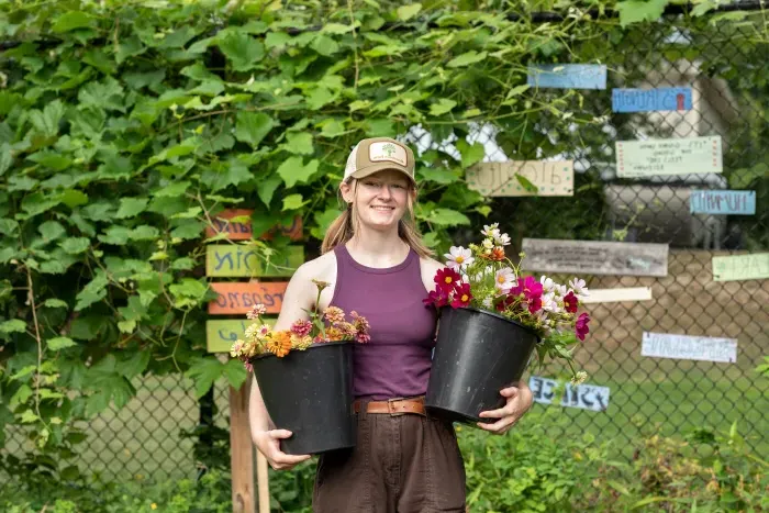 A student carrying two potted plants.
